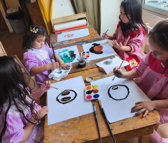 Niñas pintan sus autorretratos alrededor de una mesa